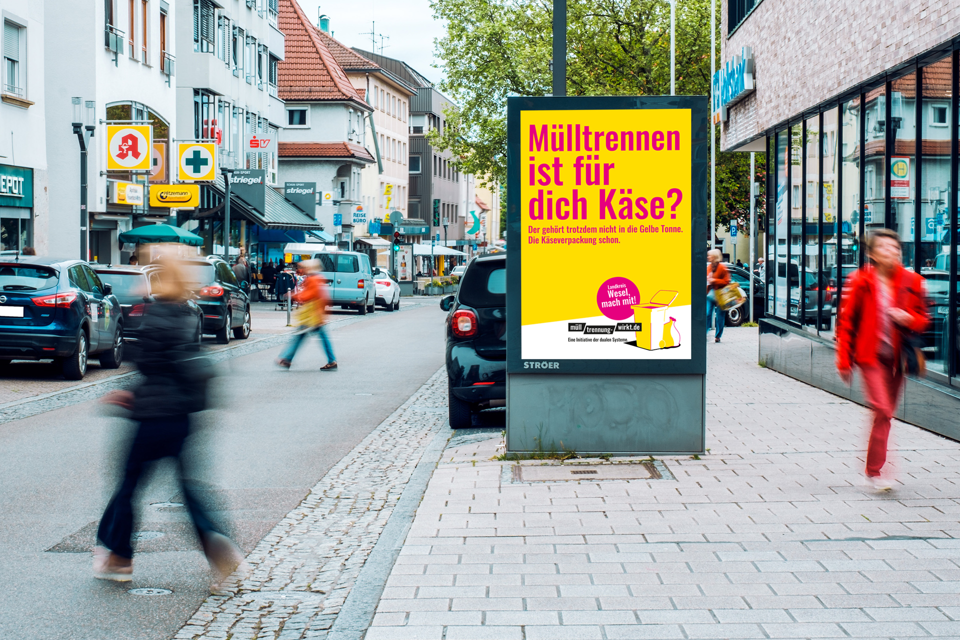 Straßenszene mit Plakat zur Mülltrennung, Text 'Mülltrennen ist für dich Käse?' auf gelbem Hintergrund an einer Bushaltestelle